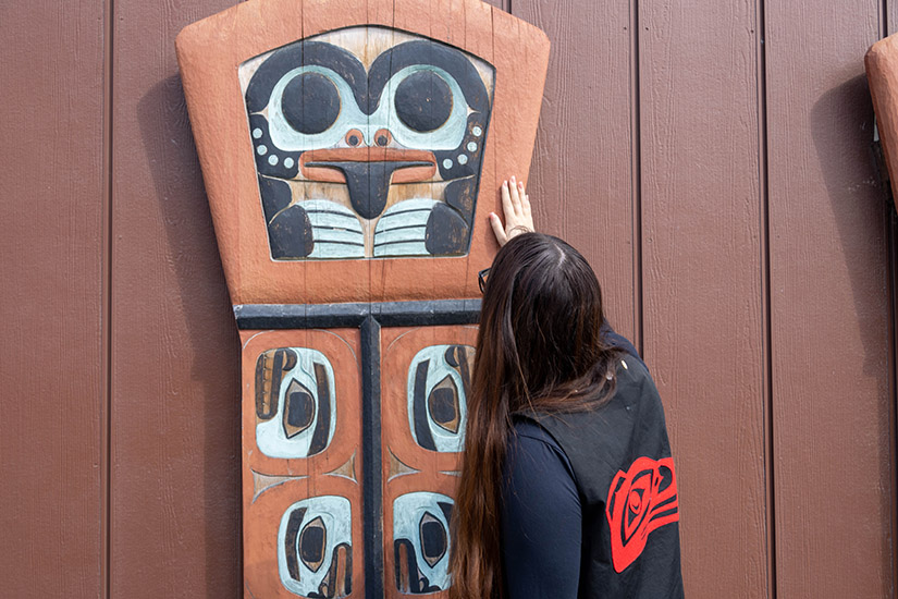 A person places their hand on a carving.