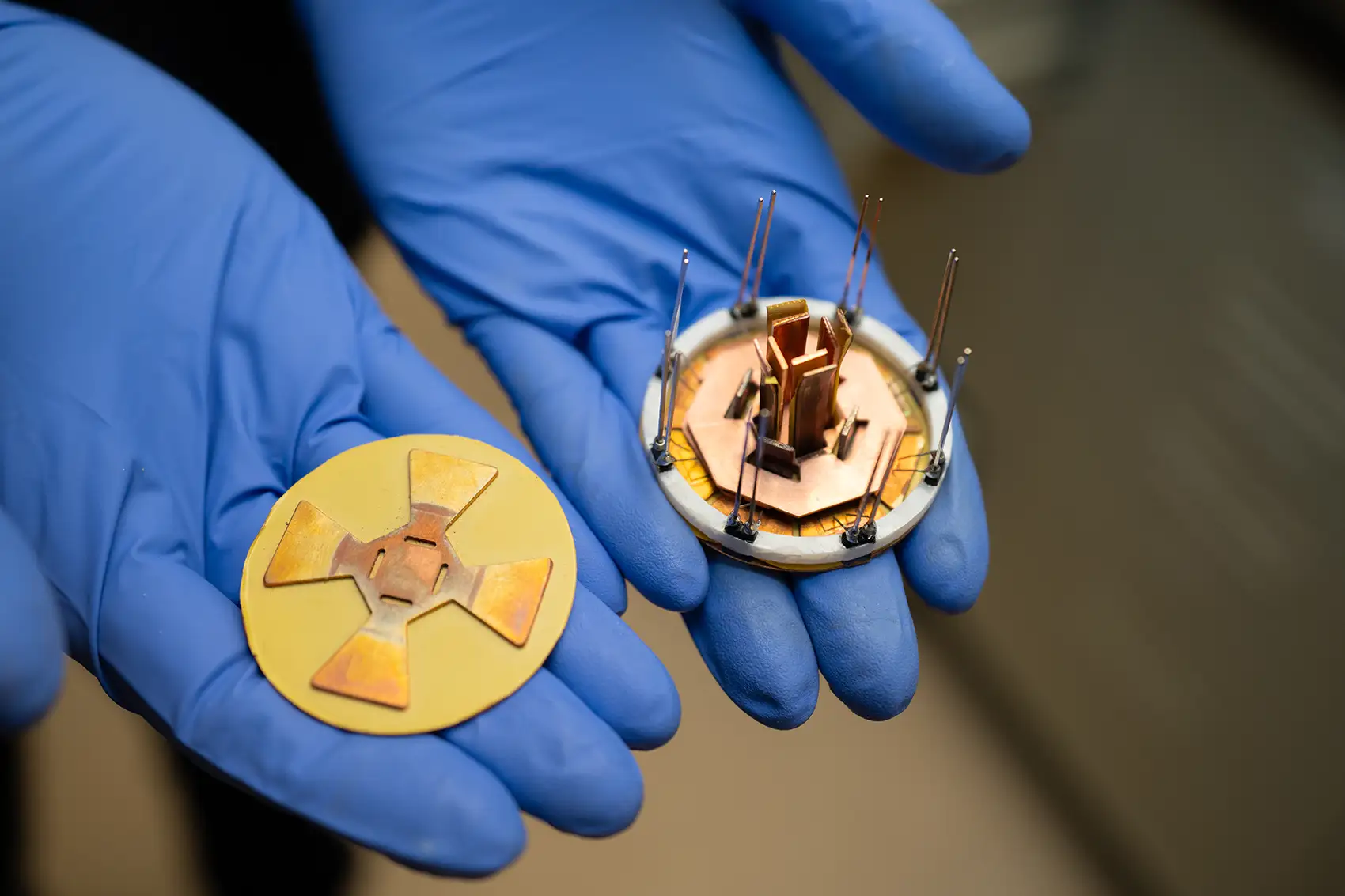 20250818-nrel-researchers-build-worlds-fastest-low-cost-ultra-efficient-silicon-carbide-power-module-100033 Two gloved hands hold a small octagonal power module and a corresponding attachment layer.