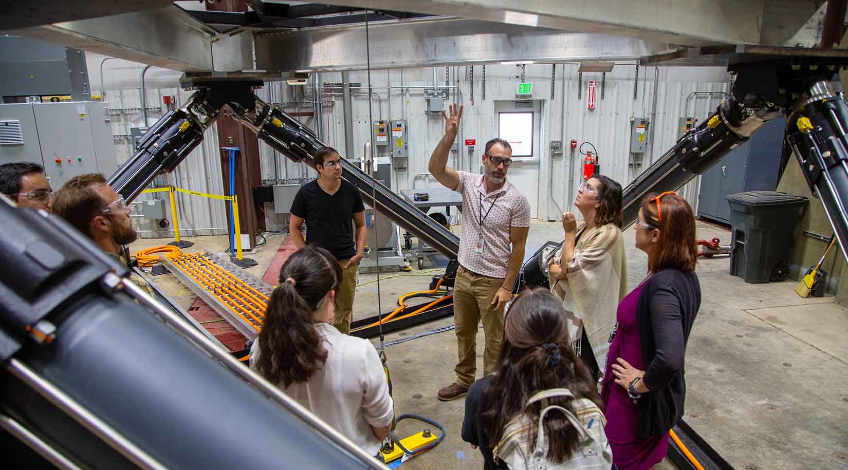 A photo of a group of people standing underneath large machinery.
